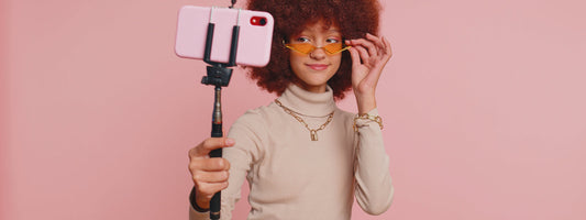 Influencer holding a selfie stick and phone.