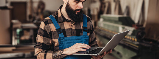Small business owner looks at his laptop in his store and shop.