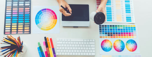 A designer drawing on a design pad with a lot of different graphic aids next to him