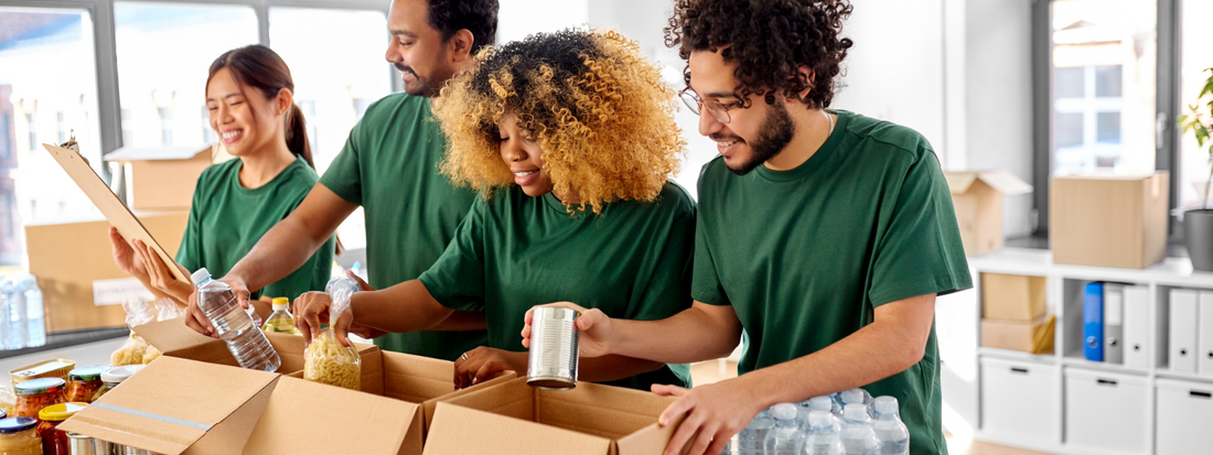 4 people at a nonprofit wearing green t-shirts placing food into boxes.