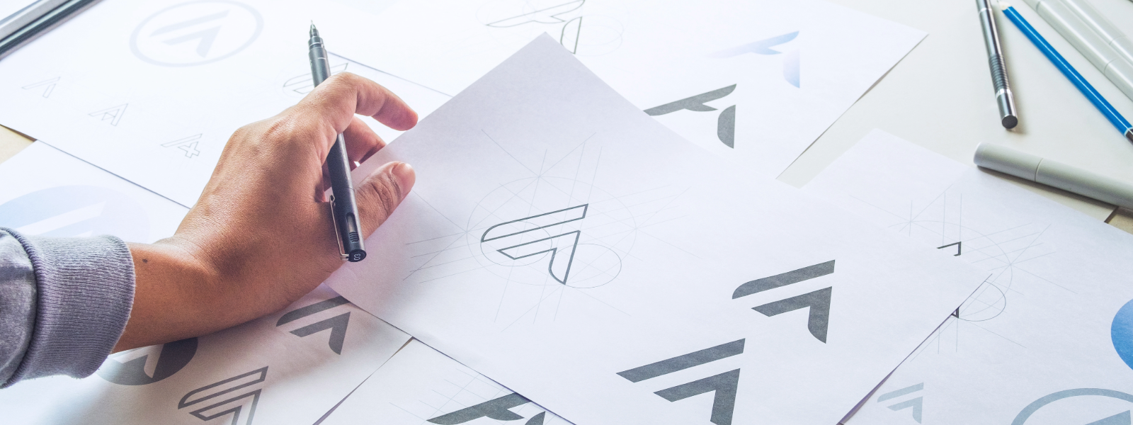 Branding logos on a sheet of paper with a man holding a pen.