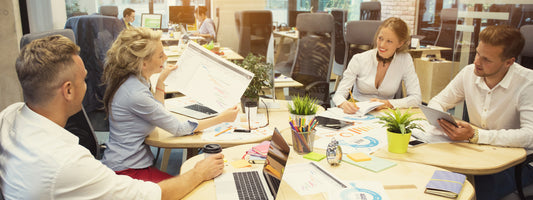 Group of people working together on a graphic design project at a table in an office.