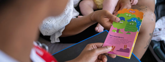 A doctor handing a mother a children's care brochure.