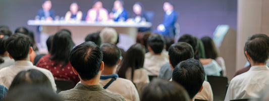 Business event with people watching a group talk around a table.